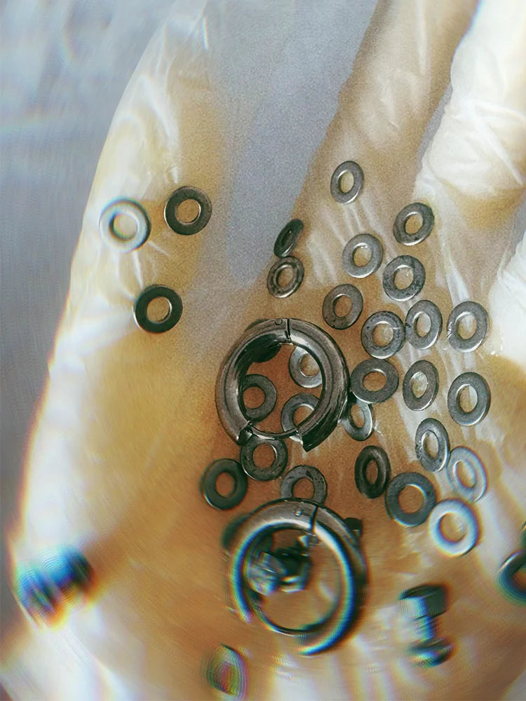 Fish Eye earrings placed with metal screw, creating contrast of jewelry and industrial element.